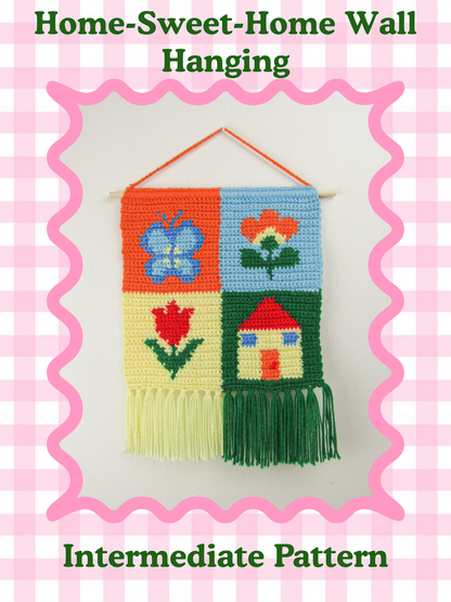 Pattern cover of a crochet wall hanging with patchwork design and tapestry art (a butterfly, two flowers and a house), lying with scissors and lavender flowers with the text title 'home sweet home all hanging' and skill level 'intermediate' around it.