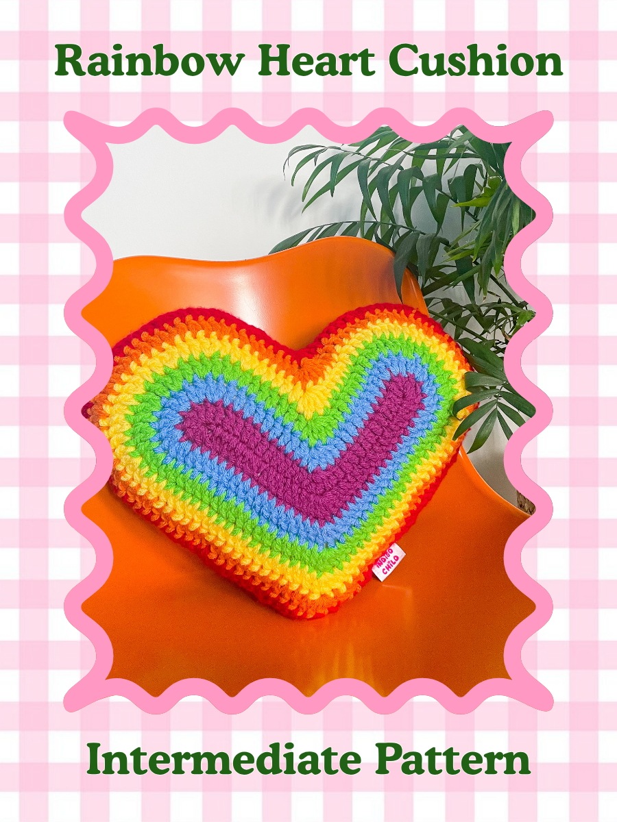 Pattern cover of a crochet pillow shaped like a heart in rainbow colours sat on an orange desk chair with the words 'rainbow heart cushion pillow' and skill level 'intermediate'.