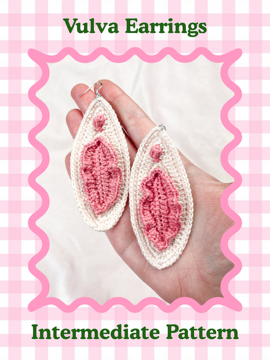 Crochet pattern cover of a hand holding a pair of cream earrings resembling vulvas with pink details and the words 'vulva earrings' and the skill level 'intermediate' on it.